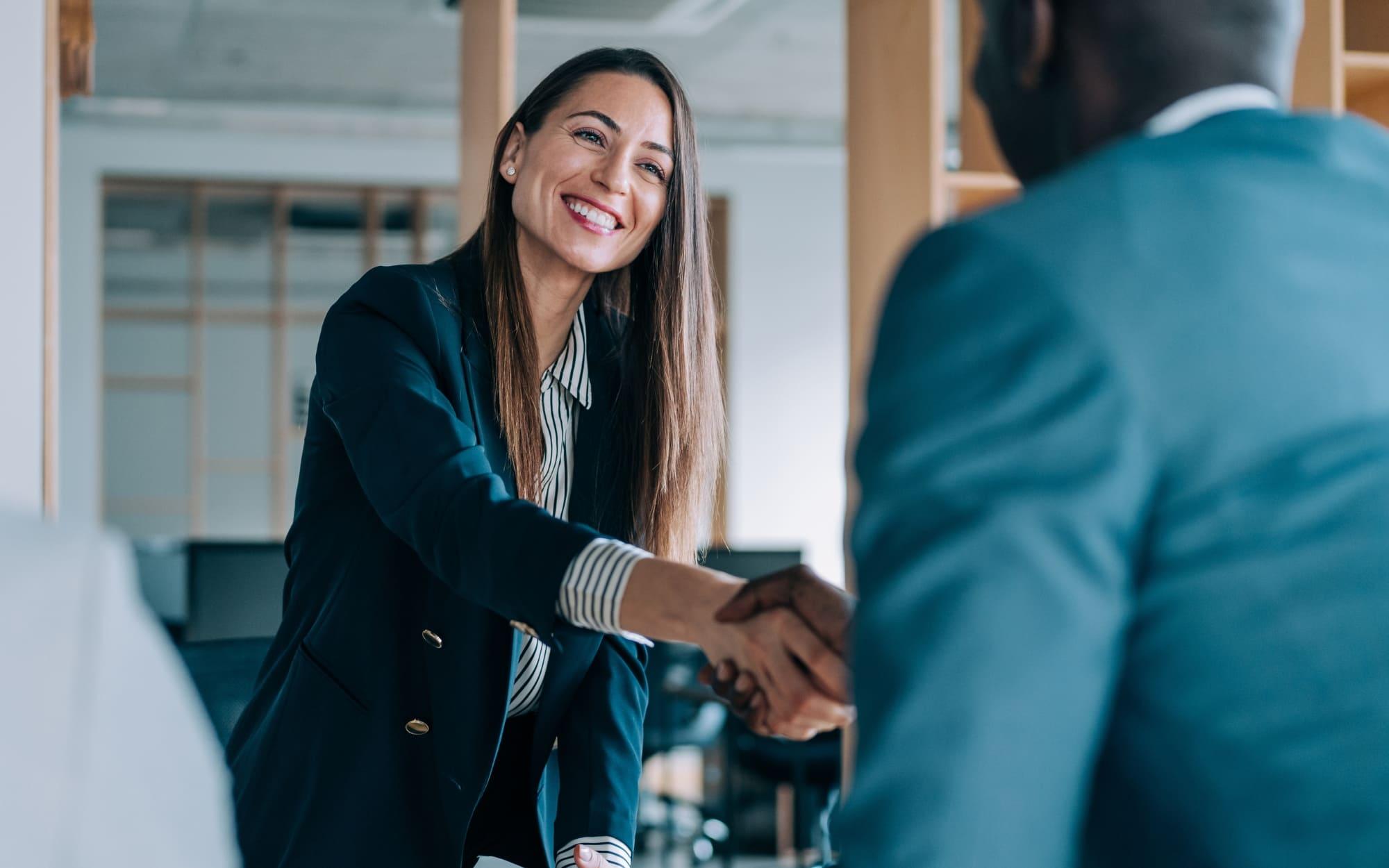 Smiling woman that is shaking hand with a man to reach an agreement
